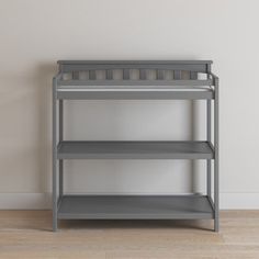 a gray shelf sitting on top of a hard wood floor next to a white wall