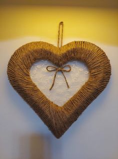 a heart shaped decoration hanging on a wall with a string tied to it's side