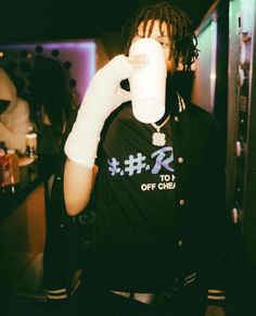 a man with dreadlocks drinking from a paper cup