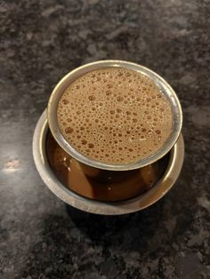 a metal cup filled with liquid on top of a table