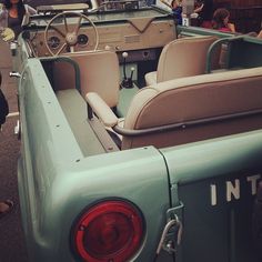 people are standing around in the back of an old green truck with seats on it