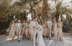 a bride and groom walking with their bridal party in front of some palm trees