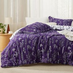 a bed with purple comforter and white pillows