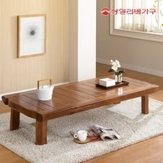 a wooden table sitting on top of a white rug in a living room next to a window