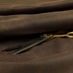 a pair of scissors sitting on top of a brown cloth