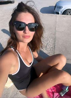 a woman sitting on the ground wearing sunglasses