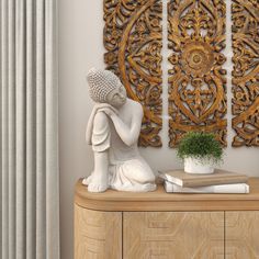 a white statue sitting on top of a wooden dresser next to a plant and book