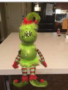 a green stuffed animal sitting on top of a counter