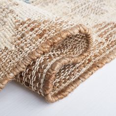 a close up view of a woven rug on a white tablecloth with brown and tan stripes