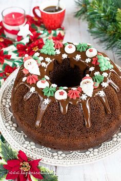 a chocolate bundt cake with frosting on a white plate next to christmas decorations