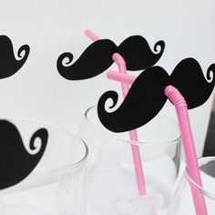 two glasses with straws in the shape of moustaches, one pink and one black