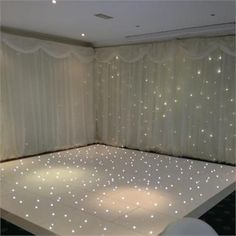 a dance floor with lights on it in front of a curtained wall and window