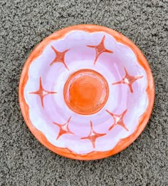 an orange and white bowl on the ground