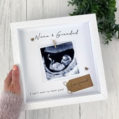 a person holding up a framed photo with the words daddy on it and a baby's boot