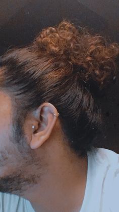 a man with curly hair and piercing on his ear