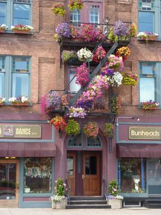 a tall building with flowers on the balconies and windows above it's entrance