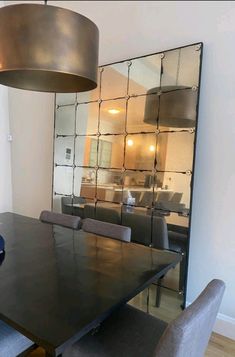 a dining room table with chairs and a large mirror in the back wall behind it