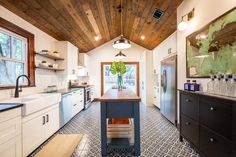 a kitchen with white cabinets and wooden ceiling