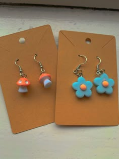 two earrings with blue and orange flowers are sitting next to each other on a card