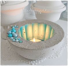 a lit candle in a concrete bowl on a doily