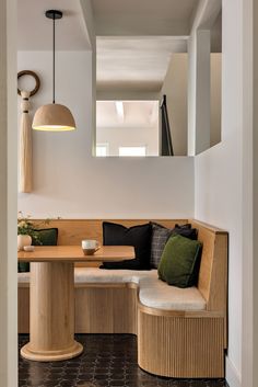 a wooden bench sitting under a mirror next to a table with pillows on top of it