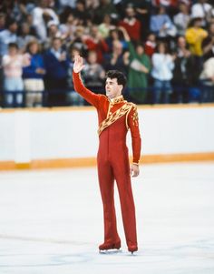 an olympic figure waves to the crowd as he stands in front of his skating rink