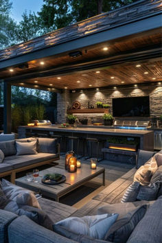 an outdoor living area with couches, tables and grill in the background at night