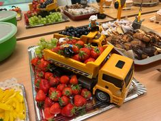 a table filled with trays of food and plates of fruit on top of it