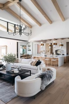 a living room filled with furniture next to a kitchen and dining room table on top of a hard wood floor