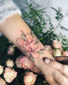 a woman's arm with a pink flower tattoo on the left side of her arm