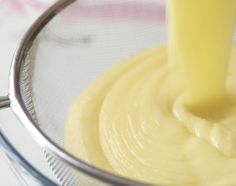 a yellow liquid being poured into a glass bowl