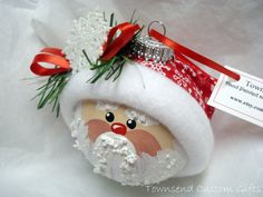 a santa clause ornament hanging from a red ribbon on a white cloth background