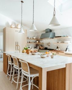 a large kitchen island with chairs and lights hanging from it's ceiling over the counter