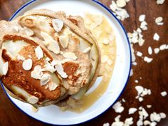 two pancakes on a plate with almonds and syrup