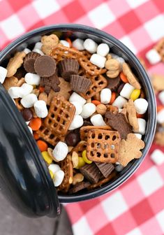 a bowl filled with candy and marshmallows on top of a checkered table cloth