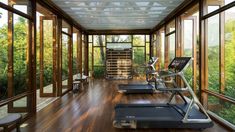 there are many treadmills in the room with glass walls and windows on both sides