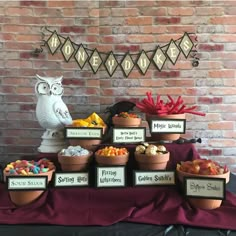 a table topped with lots of bowls filled with candy next to a sign that says halloween