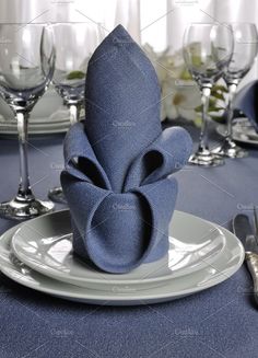 an elegant table setting with blue linen napkins and silverware on the place settings