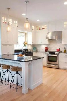 a large kitchen with white cabinets and black counter tops, an island in the middle