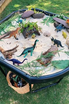 an outdoor sand and water play table with dinosaurs in it