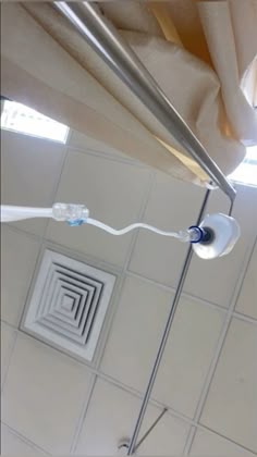 a shower head is connected to the side of a shower rod in a tiled bathroom