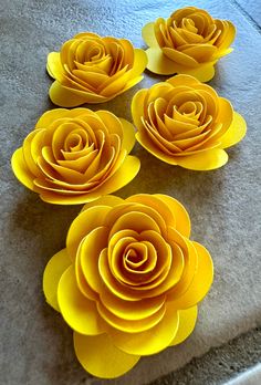 four yellow paper flowers sitting on top of a table