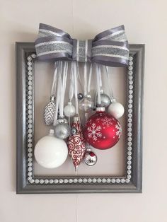 a frame with ornaments hanging from it's sides and a bow on the top