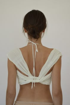 the back of a woman wearing a white top and tan panties with her hands on her hips