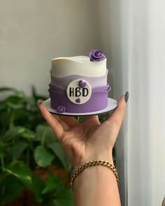 a hand holding a cake with the word hbd on it