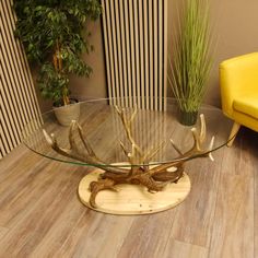 a glass table with deer antlers on it in a living room next to a yellow chair