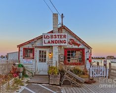 an old building sitting on top of a wooden pier next to the ocean at sunset