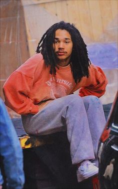 a man with dreadlocks sitting on top of a car