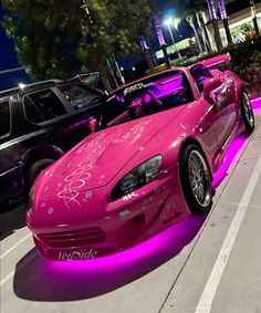 a pink sports car is parked on the street