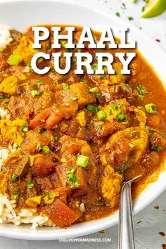 a white bowl filled with curry and rice on top of a table next to a fork